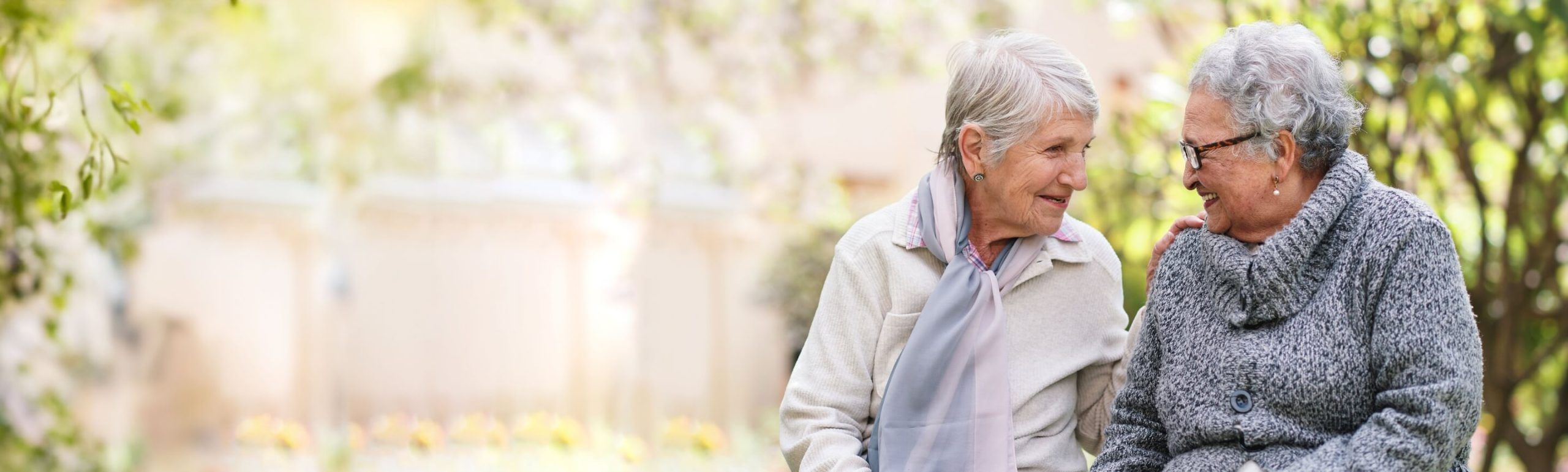 Two older women sitting and talking outside